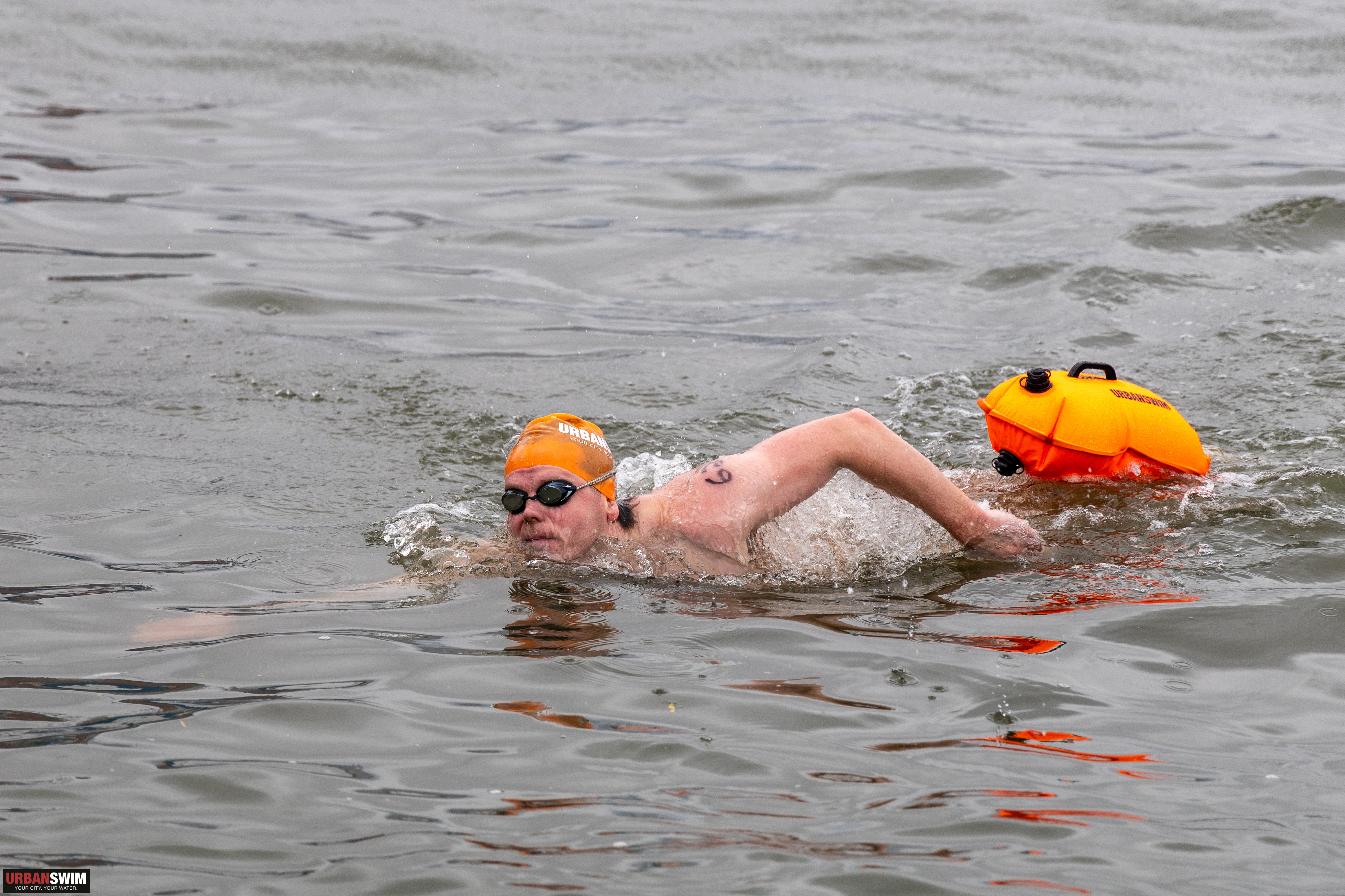Open water swimmer with tow buoy in choppy gray water